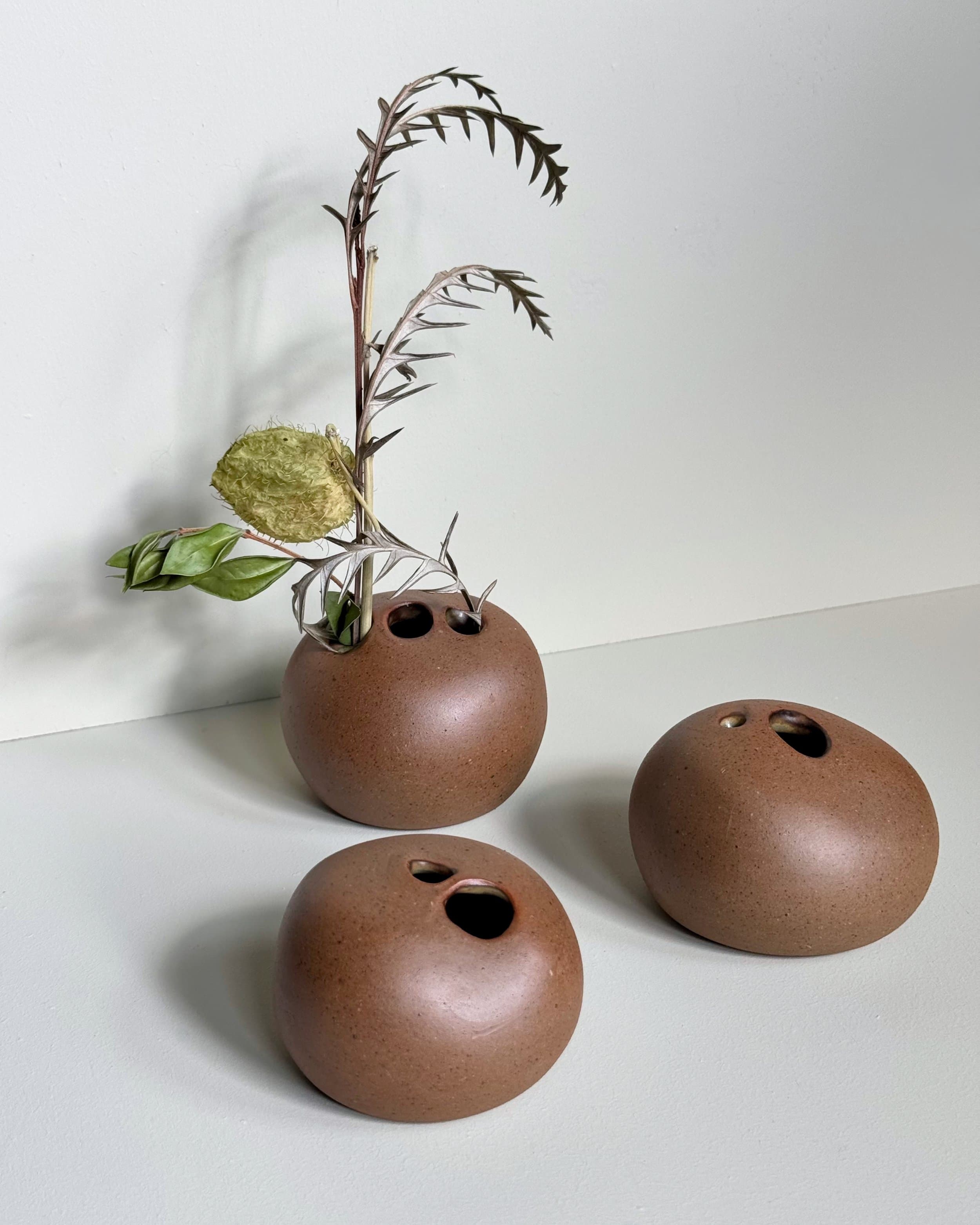 Trio of chocolate rose stone bud vases holding flowers